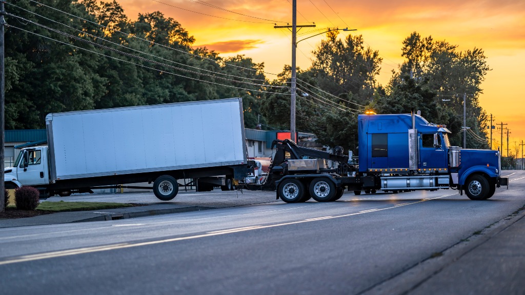 blue tow truck loads car on road after accident