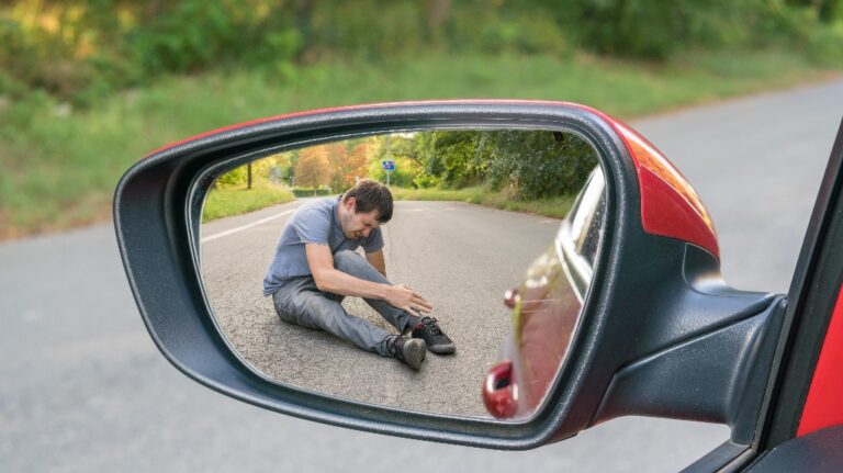 View on injured man on road in rear mirror of a car