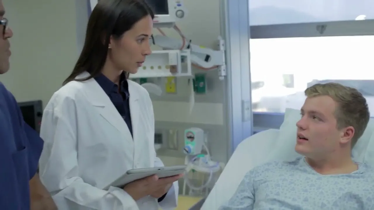 Medical professionals consulting with a male patient in a hospital room.