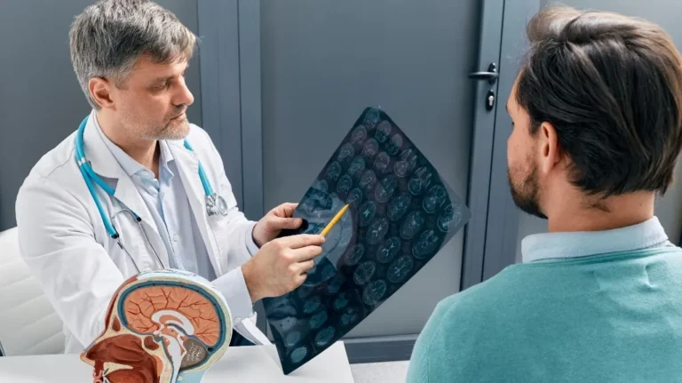 Doctor in white coat with stethoscope reviewing brain scans with male patient.